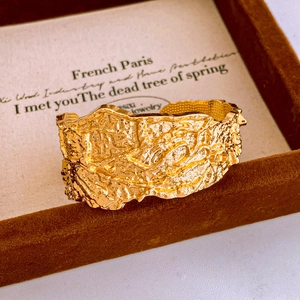Macro shot of gold wide open cuff bracelet with vintage branch lava texture on velvet tray