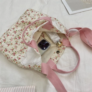 Detailed close-up of a floral canvas tote with delicate white lace trim and pink handles