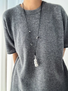 Detail of silver peanut pendant with rhinestones on a black cord worn by a model