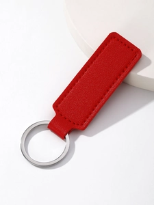 Detail of red PU leather keychain with silver metal ring on a white stone tray
