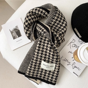 Flat lay of knit houndstooth scarf with beret and coffee for cozy winter styling