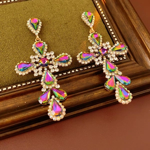 Detailed shot of vintage gold cross earrings with rainbow crystals on leather background