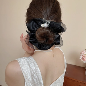 Detailed view of black satin and mesh hair scrunchie with pearls worn on a bun hairstyle