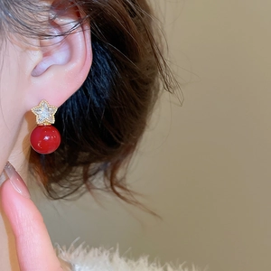 Close-up of elegant gold star studs with zircons and vintage dark red pearl drops