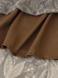 Close-up of chiffon paisley print fabric with brown lining and detailed hem stitching