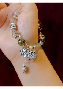 Close-up of vintage beaded bracelet with silver charms and fú bag pendant on hand