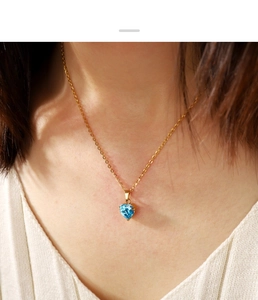 Dettaglio del ciondolo a cuore in zircone blu su una catena in acciaio inossidabile dorato