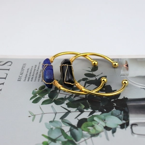 Detailed shot of handmade gold wire wrapped natural blue and black raw stone open bangles