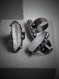 Macro shot of large raw quartz crystal pillars on vintage bronze handmade rings