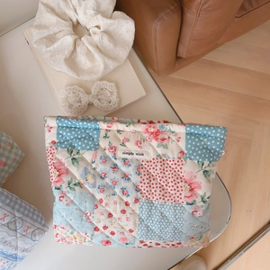 Detailed close-up of quilted floral cosmetic bag with Simple Wish label and stitching