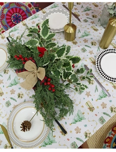 Close-up of Christmas table runner with pine branches, berries and rustic burlap bow decor