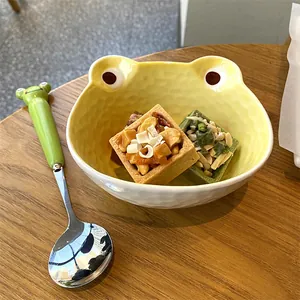 Detail of creative frog-shaped ceramic bowl and matching spoon set on a wooden table