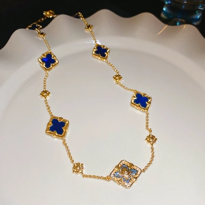 Detailed view of gold-plated geometric flower necklace with blue clover pendants on ceramic plate