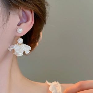Close-up of elegant floral tassel earrings with white pearls on a female model