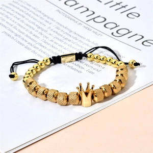 Detailed view of adjustable golden beaded bracelet with crown charm on fashion magazine
