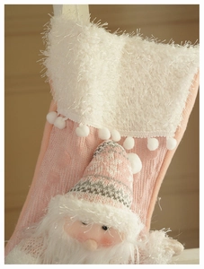 Detail of pink knitted Christmas stocking with 3D Santa Claus and plush pom-poms