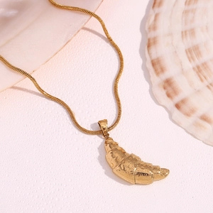 Close-up of 18K gold plated croissant pendant with fine snake chain on water droplets background