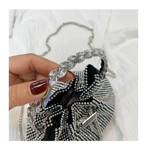 Detail of black rhinestone bucket bag with sparkling crystal handle and chain strap