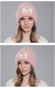 Detail of pink knitted winter beanie with premium rabbit fur texture and woven patch