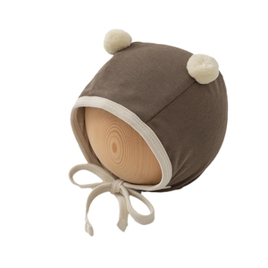 Brown newborn baby bonnet with white pom-poms and ribbed ties for ear protection