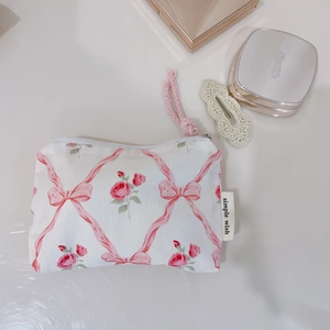 Macro detail of pink floral cotton pouch with ribbon pattern and soft cotton rope zipper