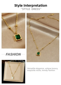 Close-up of gold-plated necklace featuring square-cut emerald and clear crystal pendants
