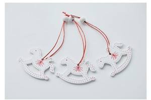 Close-up of three red and white wooden rocking horse ornaments with red hanging strings