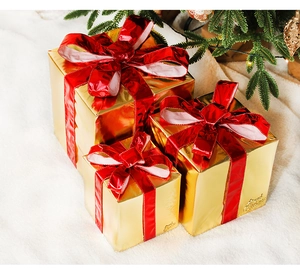 Close-up of golden Christmas gift boxes with red ribbons on a white faux fur rug
