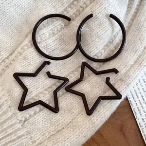 Minimalist dark brown acrylic star and hoop earrings set on cozy knit background