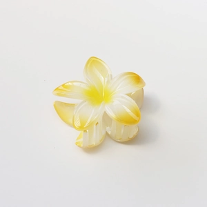 Close-up of white and yellow plumeria hair claw clip with a glossy resin finish