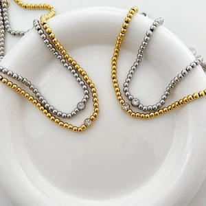Minimalist beaded chain necklace in gold and silver with a central sparkling zircon stone
