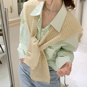 Beige knit shawl over green shirt with embroidered logo for elegant layering style
