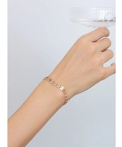 Dettaglio di un bracciale a maglie quadrate geometriche cave in oro rosa al polso