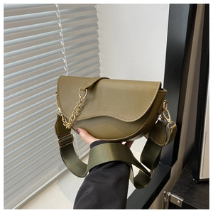 Detailed close-up of olive green saddle bag with gold chain and wide woven strap