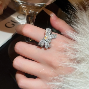Close-up of sparkling bow-shaped open ring with micro-paved zircons on silver metal