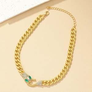Detailed view of gold snake head pendant with green crystal eyes on a chunky chain