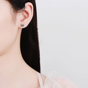 Elegant S925 sterling silver four-prong stud earrings with round moissanite on model