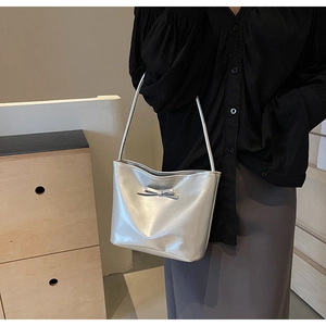 Silver leather shoulder bag with a bow decoration shown being worn by a model