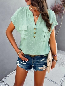 Detail of light green V-neck blouse with button-up front and textured dotted fabric