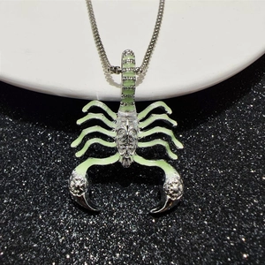 Detailed macro view of the glowing green scorpion pendant on a silver metal chain