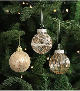 Close-up of 6cm glittery gold and white Christmas ornaments hanging on a glowing tree