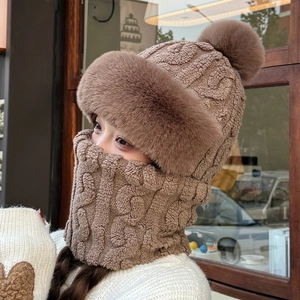 Detail showing the brown knit winter hat with fur pompom and matching fleece-lined neck gaiter