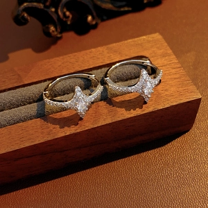 Detail of star-shaped zircon earrings displayed on a dark wood vintage jewelry stand