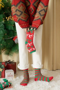 Detail von weichen Korallenvlies-Weihnachtssocken mit roten Streifen und Rentier-Mustern