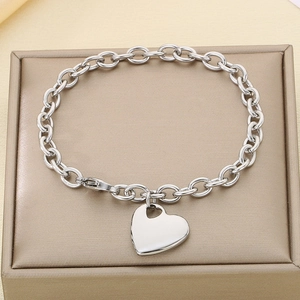 Detail of silver heart pendant on chain link bracelet resting on jewelry box