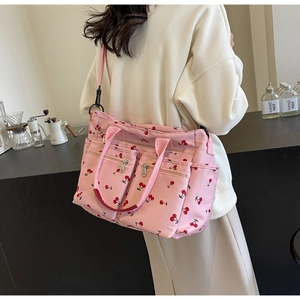 Detailed view of pink tote bag with cherry print showing side pockets and straps