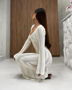 Detail of white hollow-out crochet knit dress featuring long sleeves and intricate texture
