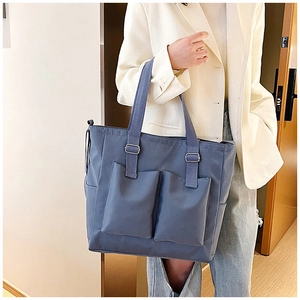 Detailed view of blue waterproof nylon tote bag with front pockets on a casual model