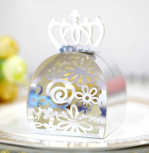 Close-up of hollow silver crown wedding favor box on a plate with floral background