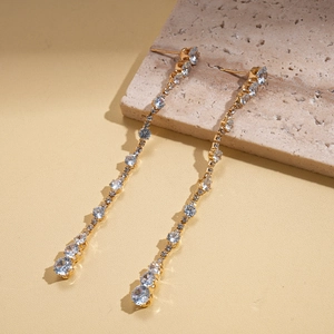 Macro detail of gold tassel earrings with zircon stones on natural stone base